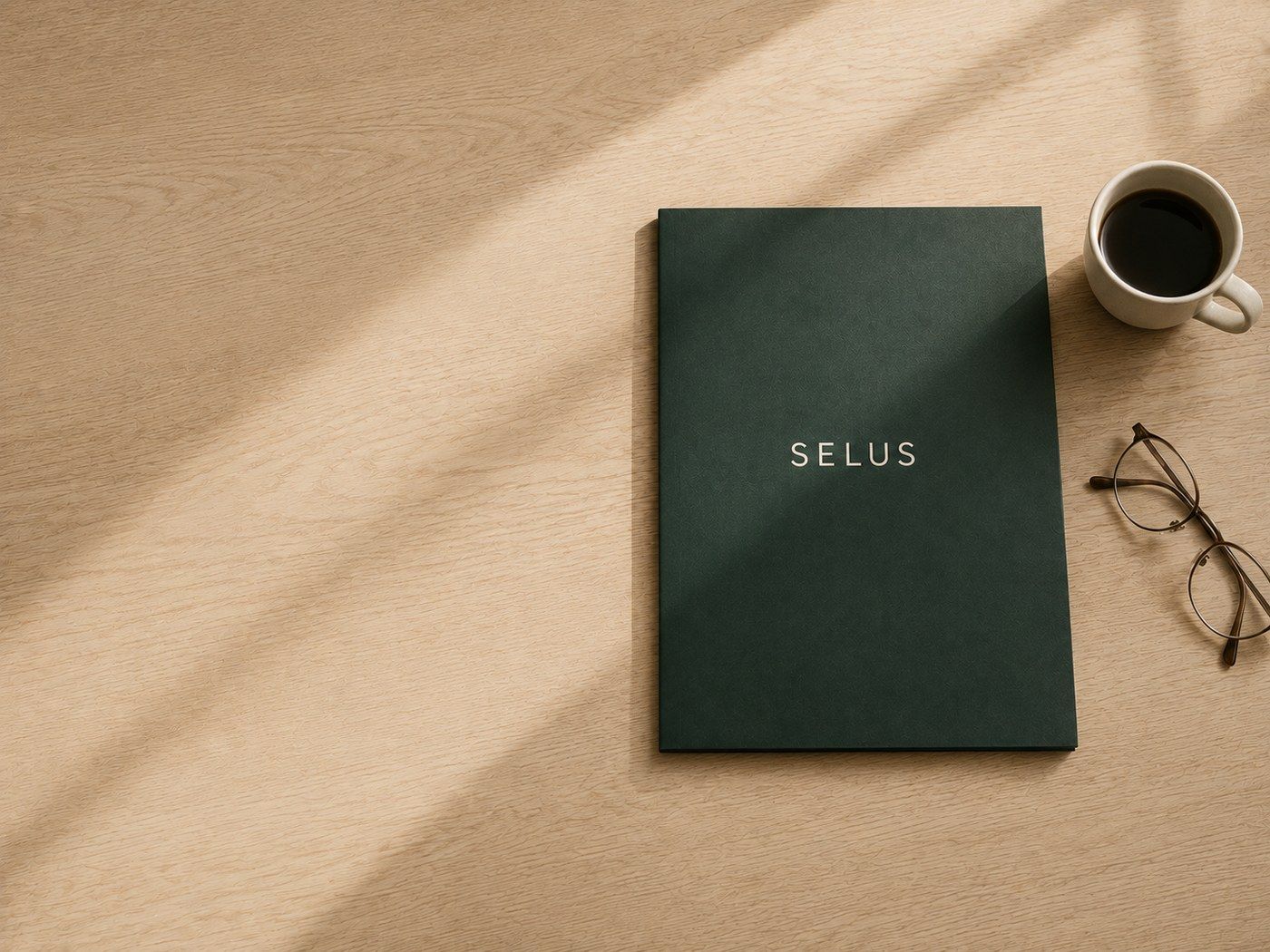 Vihreä Selus-kansio pöydällä kahvikupin ja lukulasien vieressä